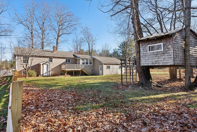 back of house with a deck, an outdoor structure, and a lawn