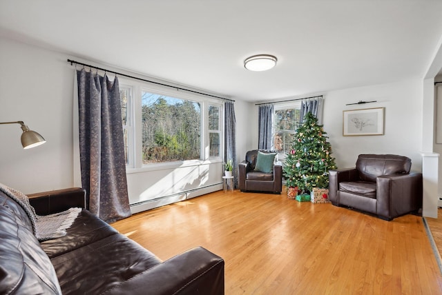 living room featuring a wealth of natural light, baseboard heating, and hardwood / wood-style floors