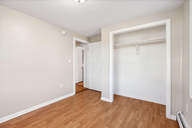 unfurnished bedroom featuring a closet, light hardwood / wood-style flooring, and a baseboard radiator