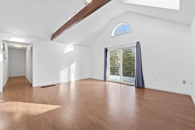 unfurnished living room featuring a healthy amount of sunlight, a skylight, high vaulted ceiling, and wood-type flooring