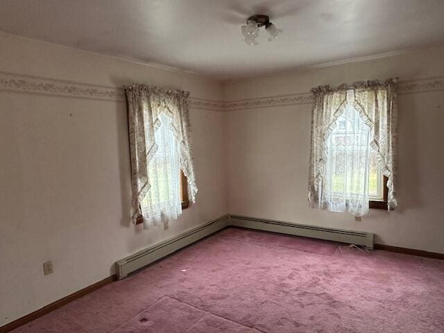 carpeted spare room with baseboard heating and a wealth of natural light