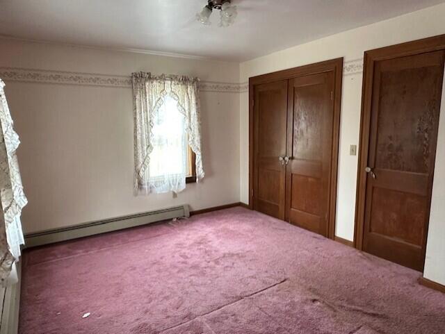 unfurnished bedroom featuring carpet floors and a baseboard radiator