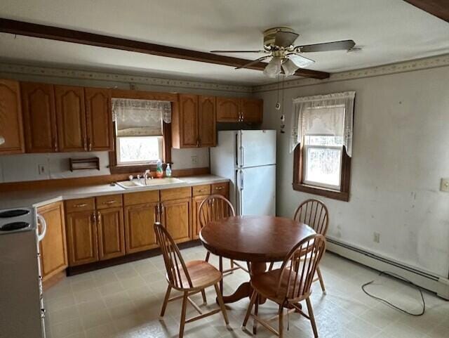 kitchen with a baseboard heating unit, sink, ceiling fan, stainless steel range, and white fridge