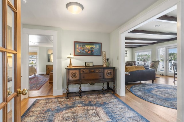 hall featuring beamed ceiling, wood-type flooring, and french doors