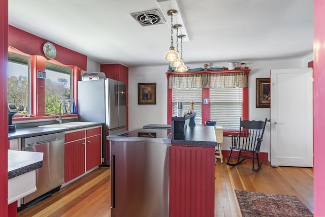 kitchen with a center island, sink, stainless steel appliances, light hardwood / wood-style flooring, and decorative light fixtures