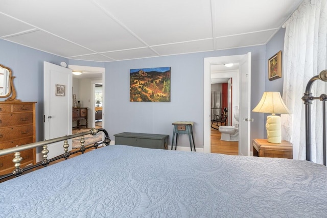 bedroom with connected bathroom and hardwood / wood-style flooring