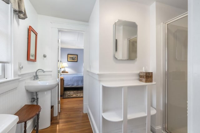 bathroom with wood-type flooring, a shower with shower door, and toilet