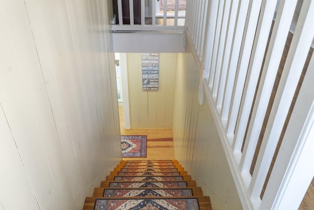 staircase with hardwood / wood-style floors and wooden walls