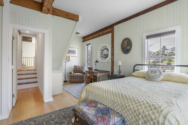 bedroom featuring beamed ceiling and light wood-type flooring