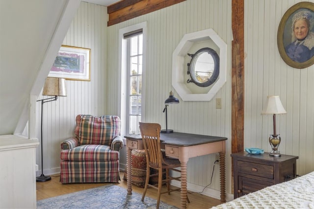 bedroom with wood walls, multiple windows, and light hardwood / wood-style flooring