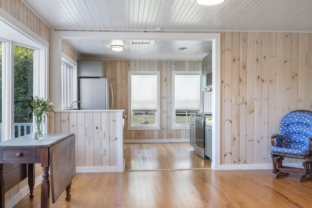 interior space with a healthy amount of sunlight, wooden walls, and light hardwood / wood-style floors