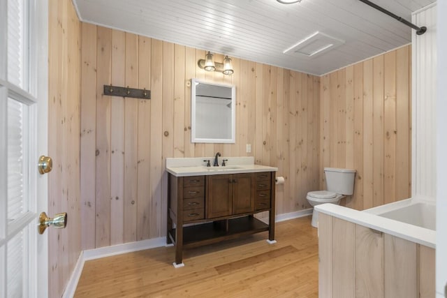 bathroom featuring wooden walls, hardwood / wood-style floors, vanity, and toilet