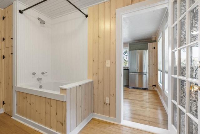 bathroom with shower / bathing tub combination, hardwood / wood-style flooring, and wood walls