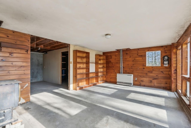 unfurnished living room featuring wooden walls and concrete floors