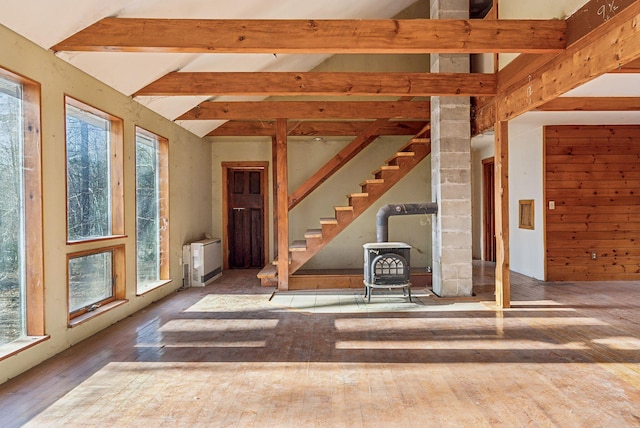 interior space with plenty of natural light, lofted ceiling with beams, a wood stove, and hardwood / wood-style flooring