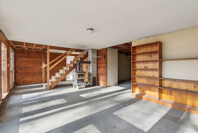 interior space with concrete floors, wood walls, and a wood stove