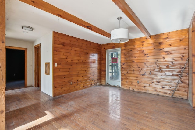 unfurnished room featuring wood walls, beamed ceiling, and wood-type flooring