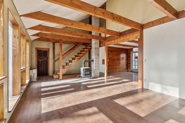 unfurnished living room with wood-type flooring, radiator heating unit, lofted ceiling with beams, and a wood stove