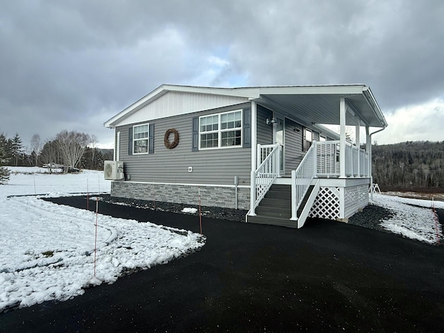 snow covered property with ac unit and a porch