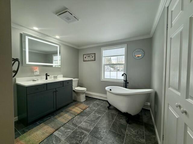 bathroom with a washtub, vanity, toilet, and crown molding