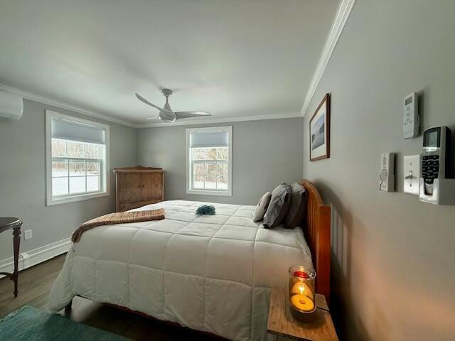 bedroom featuring ceiling fan, wood-type flooring, ornamental molding, and multiple windows