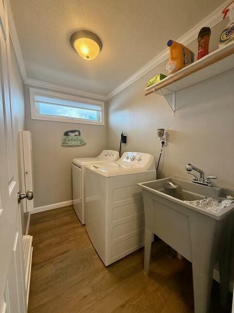 clothes washing area featuring washing machine and dryer, dark hardwood / wood-style flooring, a textured ceiling, and ornamental molding