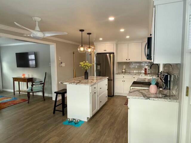 kitchen with stainless steel fridge, decorative light fixtures, a kitchen island, and white cabinets