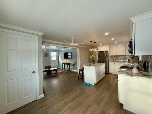 kitchen featuring white cabinets, decorative light fixtures, a center island, and stainless steel appliances