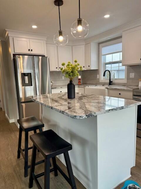 kitchen with dark hardwood / wood-style floors, a kitchen island, white cabinetry, and appliances with stainless steel finishes