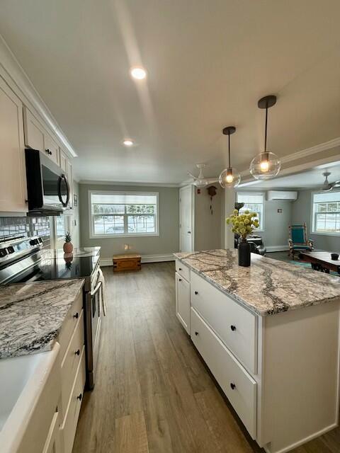 kitchen featuring a wall mounted air conditioner, white cabinets, a kitchen island, dark hardwood / wood-style flooring, and stainless steel appliances