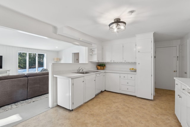 kitchen with kitchen peninsula, white cabinets, light colored carpet, and sink