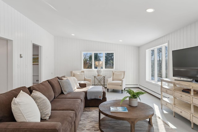 living room with baseboard heating and wood walls