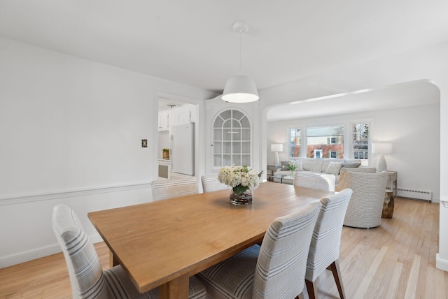 dining space with baseboard heating and light wood-type flooring