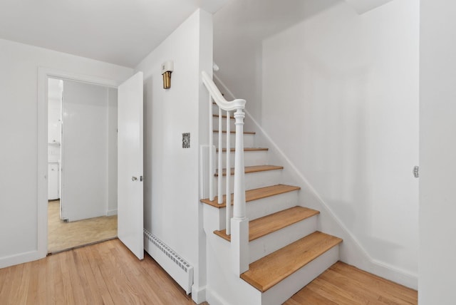 stairs featuring baseboard heating and hardwood / wood-style floors