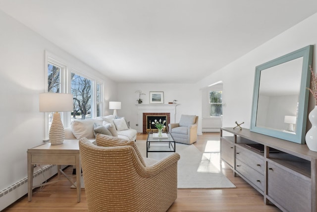 living room featuring a brick fireplace, a baseboard radiator, and light wood-type flooring