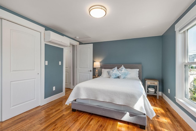 bedroom featuring a wall mounted air conditioner and light wood-type flooring