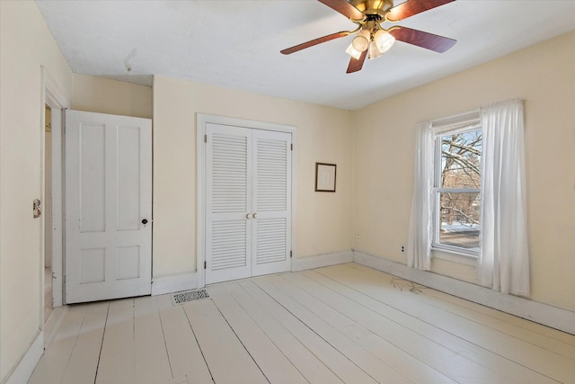 unfurnished bedroom featuring ceiling fan, a closet, and light hardwood / wood-style flooring