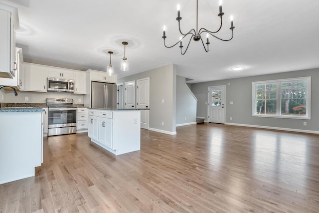 kitchen featuring stainless steel appliances, a kitchen island, light hardwood / wood-style flooring, pendant lighting, and white cabinets