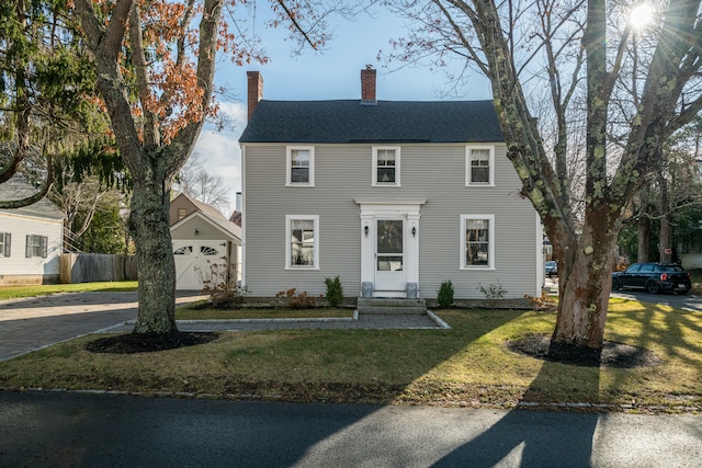 colonial inspired home featuring a front lawn and a garage