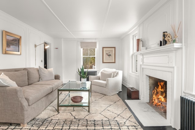 living room with radiator heating unit, hardwood / wood-style flooring, and ornamental molding