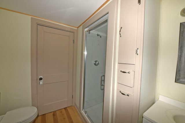 bathroom with hardwood / wood-style flooring, toilet, an enclosed shower, and vanity