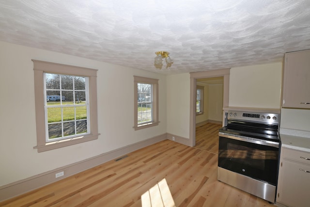 kitchen with electric range, light hardwood / wood-style floors, white cabinetry, and a textured ceiling