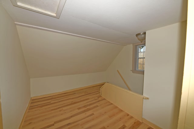 additional living space with vaulted ceiling and light hardwood / wood-style flooring