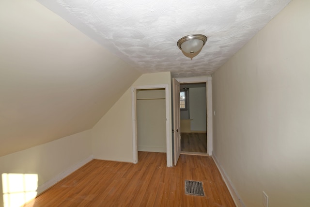 additional living space featuring light wood-type flooring and vaulted ceiling