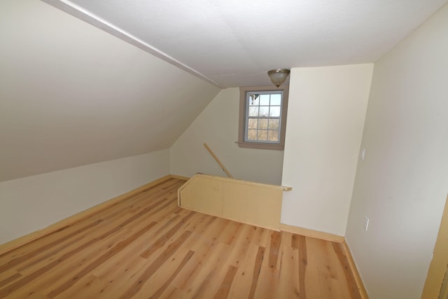 additional living space with light hardwood / wood-style flooring and vaulted ceiling