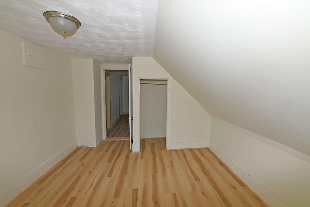 bonus room featuring light wood-type flooring and vaulted ceiling