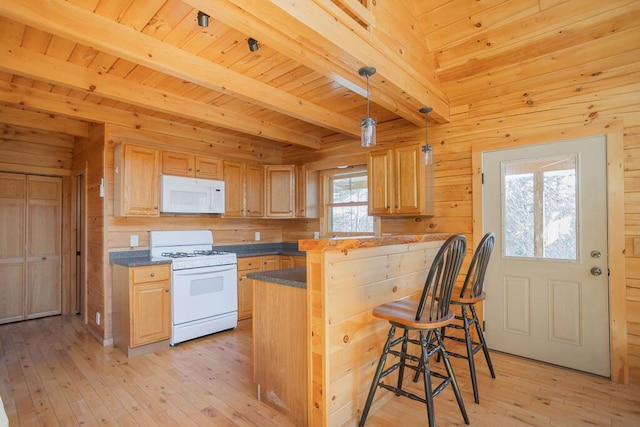 kitchen featuring light wood-type flooring, white appliances, a breakfast bar, and wood walls