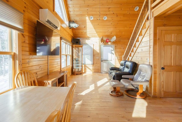 living area featuring a wall unit AC, wood walls, light hardwood / wood-style flooring, and lofted ceiling