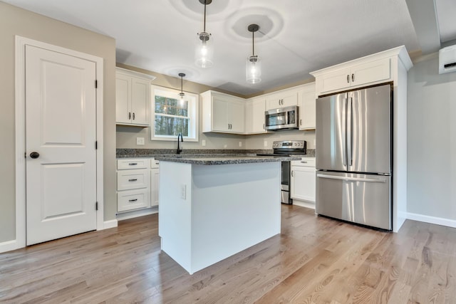 kitchen with pendant lighting, white cabinets, light wood-type flooring, and stainless steel appliances