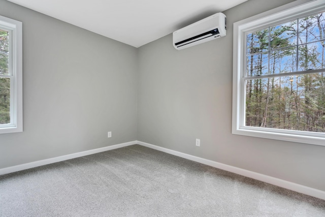 empty room with a wall unit AC, a wealth of natural light, and carpet